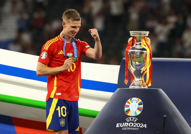 Selebrasi Dani Olmo di sebelah trofi juara saat laga Spanyol vs Inggris dalam final Piala Eropa 2024 di Olympiastadion, Berlin, Jerman, pada Senin (15/7) dini hari WIB. Foto: REUTERS/Kai Pfaffenbach