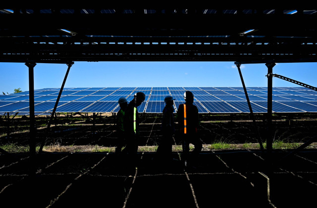 Sejumlah petugas melintas dekat panel Pembangkit Listrik Tenaga Surya (PLTS) on grid Sengkol kapasitas 7 MWp yang dioperasikan Vena Energy di Sengkol, Praya, Lombok Tengah, NTB, Senin (15/7/2024). Foto: Ahmad Subaidi/ANTARA FOTO