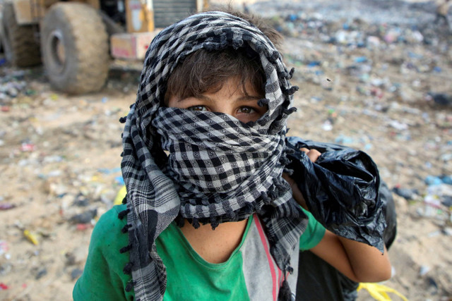 Seorang anak mencari barang-barang yang dapat digunakan di tempat pembuangan sampah di Khan Younis, Jalur Gaza, Senin (15/7/2024). Foto: Hatem Khaled/REUTERS