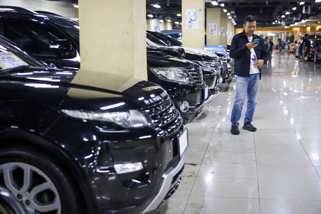 Pengunjung melihat koleksi mobil bekas yang dijual lewat gawai pintarnya di Blok M, Jakarta, Rabu (17/7/2024). Foto: Iqbal Firdaus/kumparan