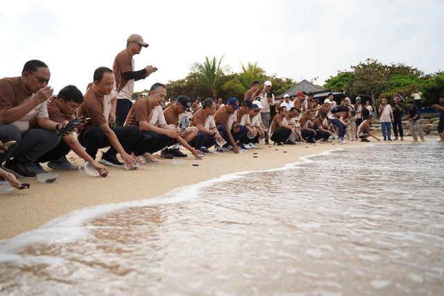 Direktur Group Business Development Telkom Indonesia, Honesti Basyir (ketiga dari kiri) dan Direktur Utama Finnet, Rakhmad Tunggal Afifuddin (ketiga dari kanan, topi hitam) saat melakukan pelepasan tukik di pantai Nusa Dua, Bali. Foto: Dok. Telkom