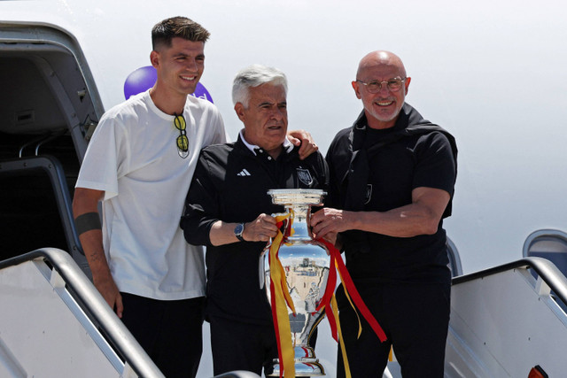 Presiden Federasi Sepak Bola Spanyol Pedro Rocha, pelatih Timnas Spanyol Luis de la Fuente dan Alvaro Morata foto bersama dengan trofi Piala Eropa 2024 saat mendarat di Bandara Adolfo Suarez Madrid-Barajas, Madrid, Spanyol, Senin (15/7/2024). Foto: Violeta Santos Moura/ REUTERS