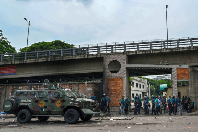 Polisi berjaga di kantor pusat lembaga penyiaran negara Bangladesh Television, setelah para mahasiswa membakarnya di tengah protes anti-kuota yang sedang berlangsung di Dhaka pada 19 Juli 2024. Foto:  Munir Uz zaman/AFP