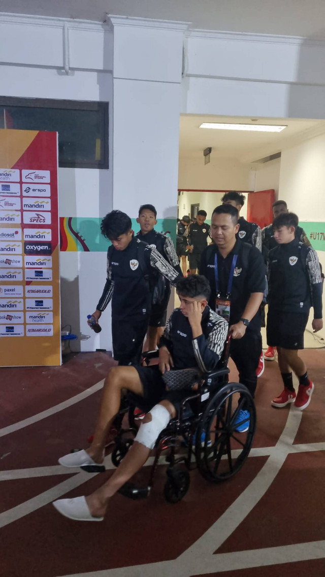 Welber Jardim naik kursi roda dibantu fisioterapis Asep Aziz usai Timnas U-19 Indonesia kalahkan Timor Leste dalam Piala AFF di Stadion Gelora Bung Tomo, Surabaya, Selasa (23/7/2024). Foto: Farusma Okta Verdian/kumparan