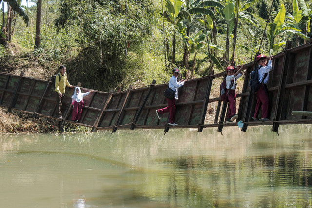 Siswa berusaha melintasi jembatan rusak di Neglasari, Lengkong, Sukabumi, Jawa Barat, Selasa (23/7/2024). Foto: ANTARA FOTO/Henry Purba