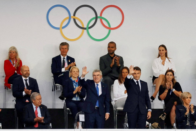 Presiden Komite Olimpiade Internasional (IOC) Thomas Bach dan Presiden Prancis Emmanuel Macron melambaikan tangan saat pembukaan Olimpiade Paris 2024 di Paris, Prancis, Sabtu (27/7/2024). Foto: Anushree Fadnavis/Reuters