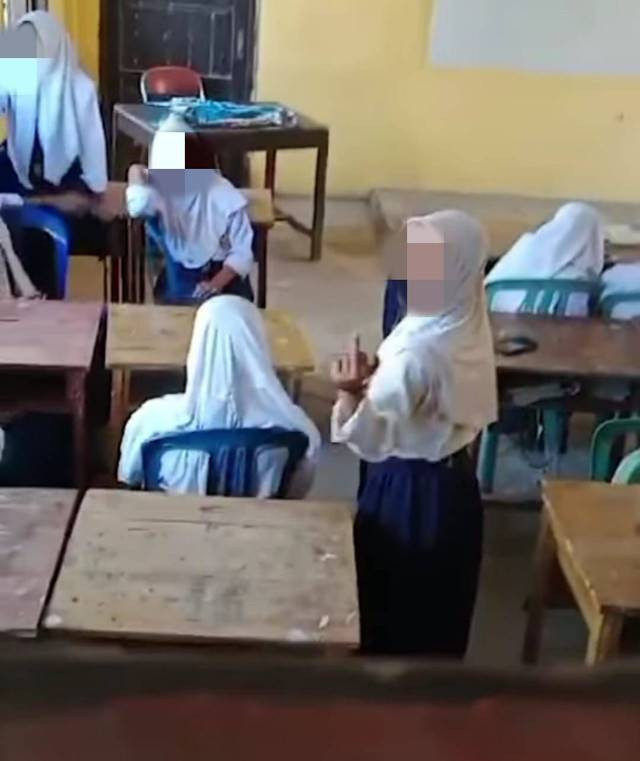 Pelaku pembullyan yang sedang melihat arah kamera sedangkan korban duduk di sampingnya, Foto : potongan video