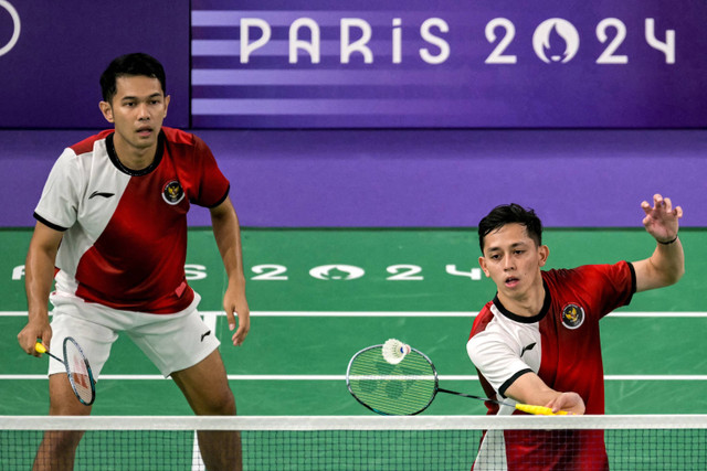 Ganda putra Indonesia Muhammad Rian Ardianto dan Fajar Alfian mengembalikan kok ke arah ganda Jerman Mark Lamsfuss/Marvin Saidel pada babak penyisihan Grup C Olimpiade Paris 2024 di Porte De La Chapella Arena, Paris, Prancis, Sabtu (27/7/2024). Foto: Arun SANKAR/AFP