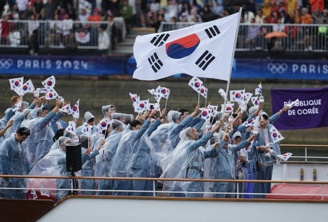 Kontingen Korea Selatan mengikuti defile dengan menaiki kapal menyusuri sungai Seine saat pembukaan Olimpiade Paris 2024 di Paris, Prancis, Kamis (26/7/2024).
 Foto: Dimitar DILKOFF / AFP