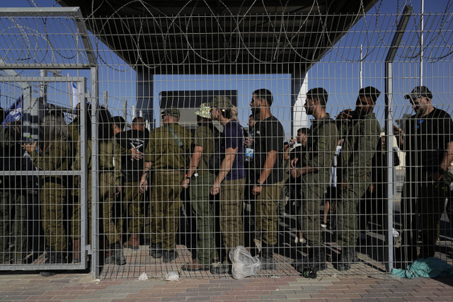 Tentara Israel berkumpul di gerbang pangkalan militer Sde Teiman, ketika orang-orang berunjuk rasa untuk mendukung para tentara yang diinterogasi atas pelecehan terhadap tahanan, Senin (29/7/2024). Foto: Tsafrir Abayov/AP Photo