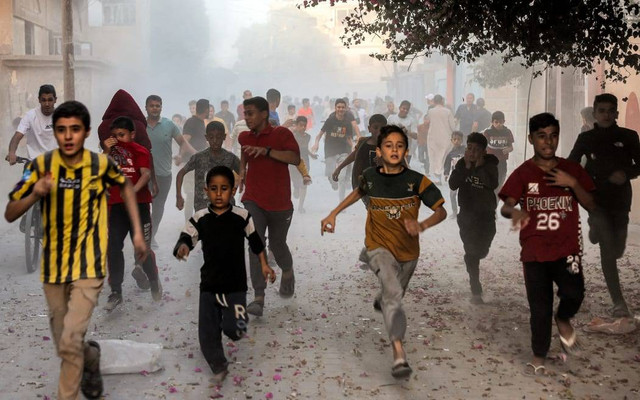 Anak-anak Gaza berlarian saat menyelamatkan diri dari bom zionis Israel. Foto: Mohammed Abed/AFP