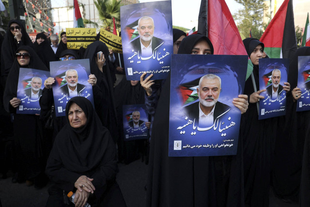 Orang-orang memegang poster pemimpin kelompok Palestina Hamas, Ismail Haniyeh dalam sebuah pertemuan anti-Israel setelah pembunuhan terhadapnya di tengah konflik yang sedang berlangsung antara Israel dan Hamas, di Teheran, Iran, Rabu (31/7/2024). Foto: Majid Asgaripour / WANA / via REUTERS