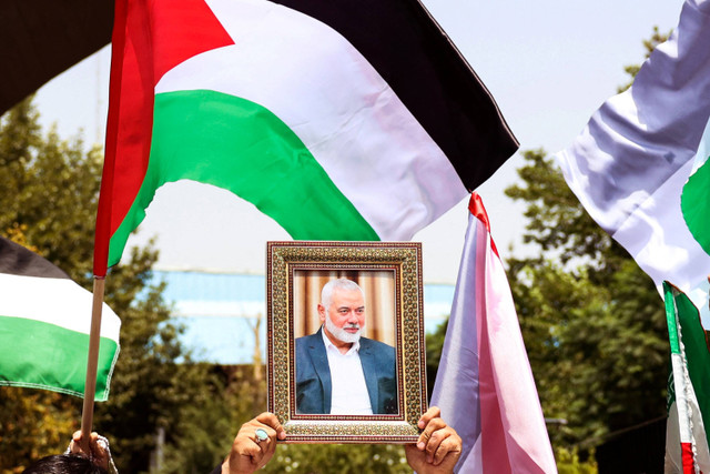 Orang-orang mengangkat bendera Palestina dan potret pemimpin Hamas yang terbunuh, Ismail Haniyeh, dalam sebuah unjuk rasa di Universitas Teheran, di ibu kota Iran, Teheran, pada 31 Juli 2024. Foto: AFP