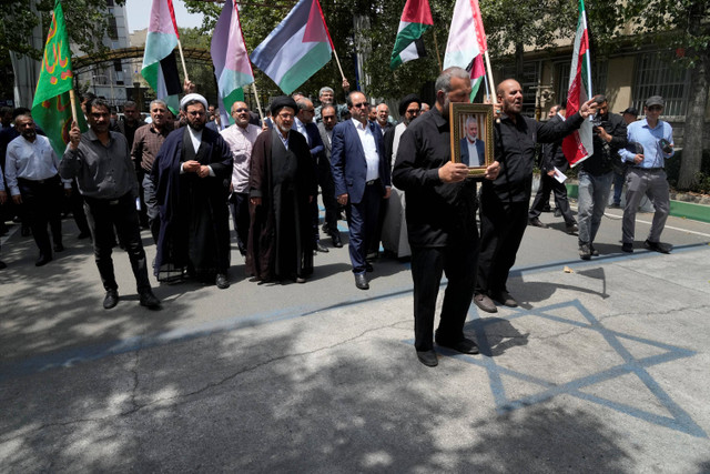 Orang-orang mengangkat bendera Palestina dan potret pemimpin Hamas yang terbunuh, Ismail Haniyeh, dalam sebuah unjuk rasa di Universitas Teheran, di ibu kota Iran, Teheran, pada 31 Juli 2024. Foto: Vahid Salemi/AP Photo