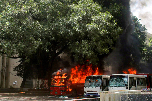 Bus di Universitas Kedokteran Bangabandhu Sheikh Mujib terbakar setelah bentrokan antara mahasiswa dan pendukung pemerintah selama protes di Dhaka, Bangladesh, Minggu (5/8/2024). Foto: Abdul GONI/AFP