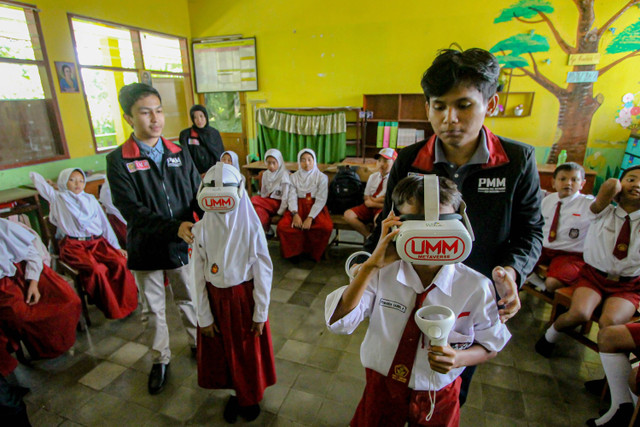 Dua mahasiswa Universitas Muhammadiyah Malang (UMM) mengarahkan siswa menggunakan teknologi virtual reality (VR) saat mengikuti kegiatan belajar mengajar di SDN 03 Tumpang, Malang, Jawa Timur, Selasa (6/8/2024). Foto: Muhammad Mada/ANTARA FOTO