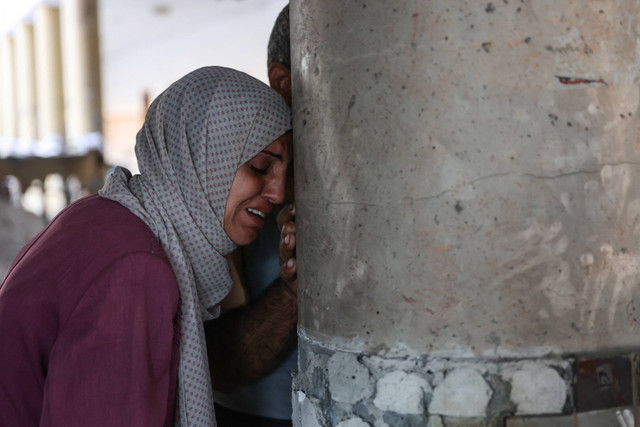 Seorang wanita menangis di dalam sekolah yang digunakan sebagai tempat penampungan sementara bagi para pengungsi Palestina setelah serangan Israel di Kota Gaza,  Sabtu (10/8/2024). Foto: Omar AL-QATTAA / AFP