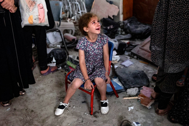 Seorang gadis kecil menangis di dalam sekolah yang digunakan sebagai tempat penampungan sementara bagi para pengungsi Palestina setelah serangan Israel di Kota Gaza,  Sabtu (10/8/2024). Foto: Omar AL-QATTAA / AFP