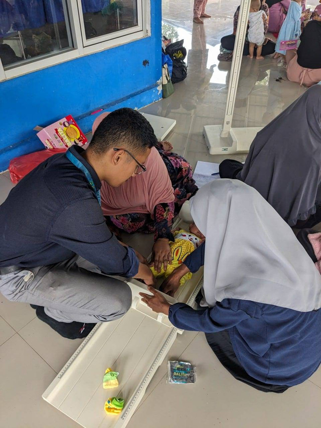 Foto penulis sedang melakukan pengukuran tinggi badan pada salah satu balita. Sumber foto: Dokumentasi pribadi)