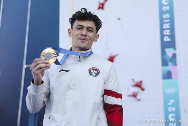 Atlet panjat tebing putra Indonesia peraih medali emas Veddriq Leonardo  mengangkat medali emasnya di podium seusai penyerahan medali final nomor speed putra Olimpiade Paris 2024, Kamis (8/8/2024). Foto: Dok. NOC Indonesia