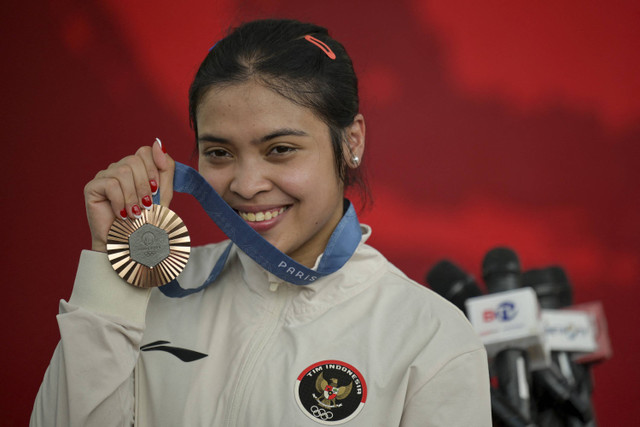 Peraih medali perunggu Indonesia cabang olahraga bulu tangkis tunggal putri Olimpiade Paris 2024, Gregoria Mariska Tunjung, berfoto dengan medali yang diraihnya di Istana Merdeka, Jakarta, Kamis (15/8/2024). Foto: Bay Ismoyo/AFP