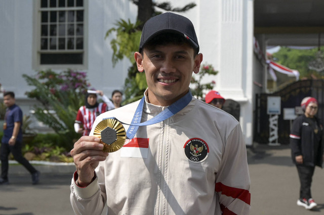 Peraih medali emas di Olimpiade Paris 2024 Veddriq Leonardo berfoto dengan medali yang di raihnya di Istana Merdeka, Jakarta, Kamis (15/8/2024). Foto: Bay Ismoyo/AFP.