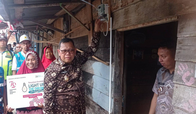 Pj Wali Kota Palembang Ucok Abdulrauf Damenta saat menyalahkan listrik di rumah warga Gandus yang menerima bantuan listrik gratis, Foto : Abdullah Toriq/Urban Id