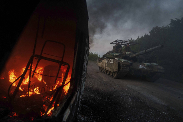 Sebuah tank Ukraina melewati mobil yang terbakar di dekat perbatasan Rusia-Ukraina, wilayah Sumy, Ukraina, Rabu, 14 Agustus 2024. Foto: AP Photo/Evgeniy Maloletka