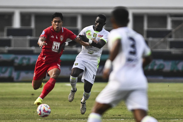 Pesepak bola Malut United FC Wahyu Prastetyo (kiri) berebut bola dengan pesepak bola Persebaya Surabaya Flavio G Silva (kedua kiri) dalam pertandingan Liga 1 di Stadion Madya, kompleks Gelora Bung Karno, Jakarta, Jumat (16/8/2024). Foto: ANTARA FOTO/Aprillio Akbar