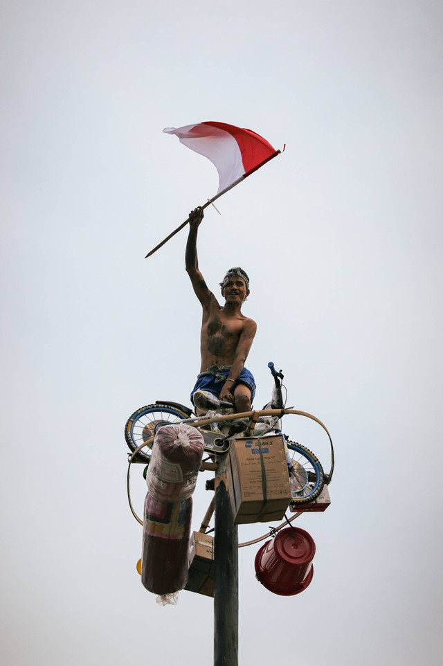 Peserta lomba panjat pinang berusaha mencapai puncak tiang untuk mengambil hadiah saat digelar lomba panjat pinang di Ancol, Jakarta, Sabtu (17/8/2024). Foto: Jamal Ramadhan/kumparan