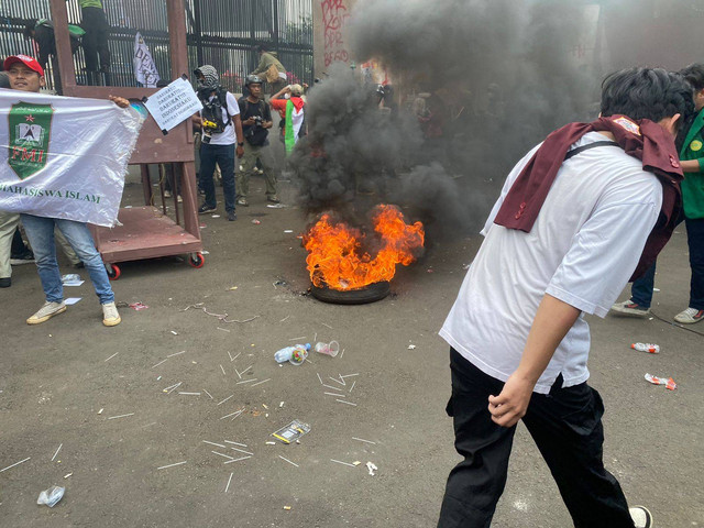 Massa aksi membakar ban dan memanjat pagar gedung MPR/DPR saat unjuk rasa RUU Pilkada, Jakarta, Kamis (22/8). Foto: Abid Raihan/kumparan