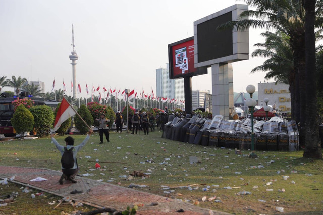 Mahasiswa membawa bendera Merah Putih saat melakukan bentrokan dengan polisi dalam aksi menolak tolak RUU Pilkada di kompleks Parlemen, Senayan, Jakarta, Kamis (22/8/2024). Foto: Jamal Ramadhan/kumparan