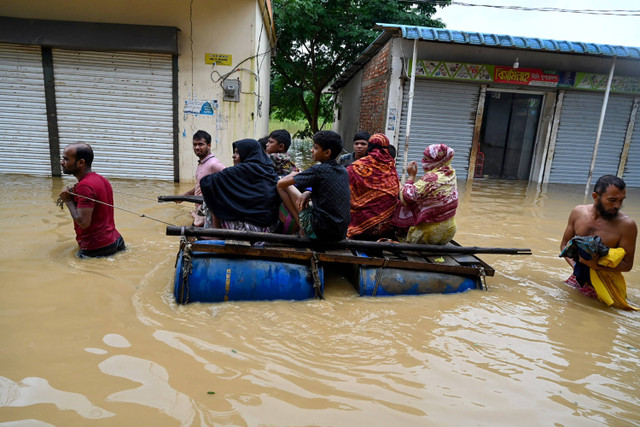 Warga menaiki perahu buatan untuk mengevakuasi saat banjir di Feni, Bangladesh, Jumat (23/8/2024). Foto:  Munir Uz zaman/AFP