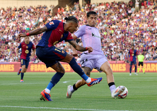 Bernat Prados coba hentikan Raphinha saat Barcelona vs Athletic Bilbao dalam laga pekan kedua Liga Spanyol 2024/25 di Estadi Olimpic Lluis Companys pada Minggu (25/8) dini hari WIB. Foto: REUTERS/Nacho Doce