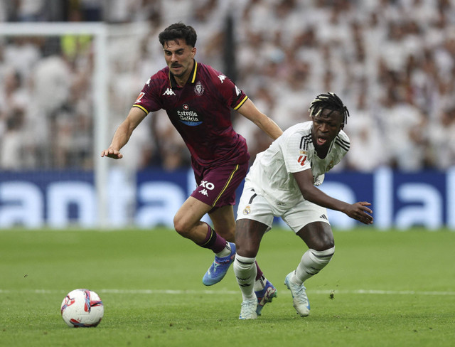 Pemain Real Madrid Vinicius Junior beraksi dengan pemain Real Valladolid Kike Perez pada pertandingan La Liga antara Real Madrid melawan Real Valladolid di Santiago Bernabeu, Madrid, Spanyol, Minggu (24/8/2024). Foto: Violeta Santos Moura/REUTERS 