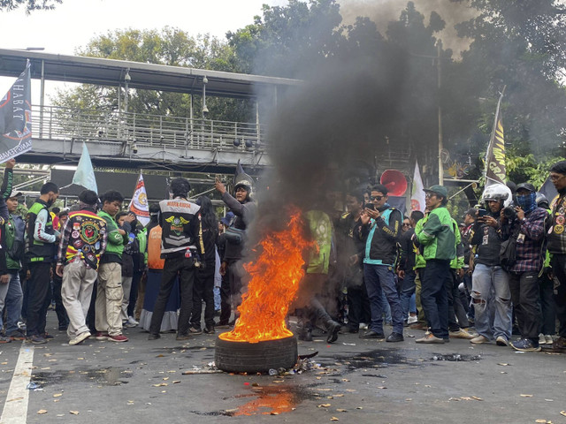 Massa aksi demonstrasi ojol-kurir mulai bakar ban akibat tak diberi akses dekati Istana Merdeka, Jakarta Pusat pada Kamis (29/8/2024). Foto: Abid Raihan/kumparan