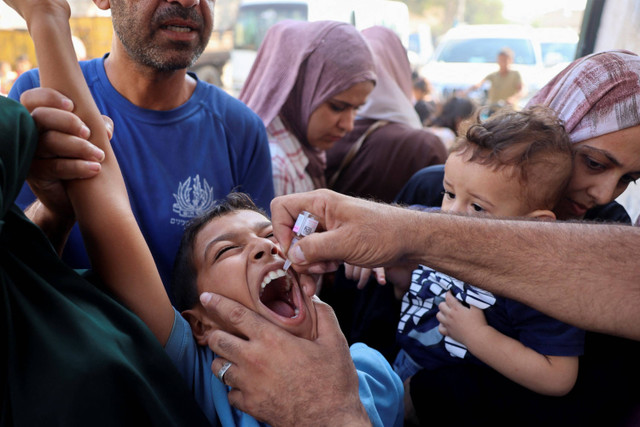 Petugas kesehatan memberikan vaksin polio kepada seorang anak Palestina di Zawayda, Jalur Gaza, Minggu (1/9/2024). Foto: Eyad BABA / AFP