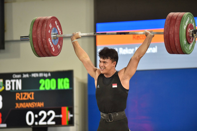 Lifter Banten Rizki Juniansyah melakukan angkatan clean and jerk saat angkat besi kelas 89 kilogram putra PON XXI Aceh-Sumut 2024 di GOR Seuramoe Angkat Besi Harapan Bangsa, Banda Aceh, Aceh, Sabtu (7/9/2024). Foto: Budi Chandra Setya/ANTARA FOTO