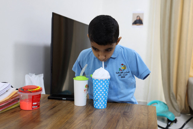 Mahmoud Ajjour, seorang anak yang terluka dan dievakuasi dari Gaza, minum air di rumahnya sambil bersiap berangkat ke sekolah, di Doha, Qatar. Foto: Ibraheem Abu Mustafa/REUTERS 