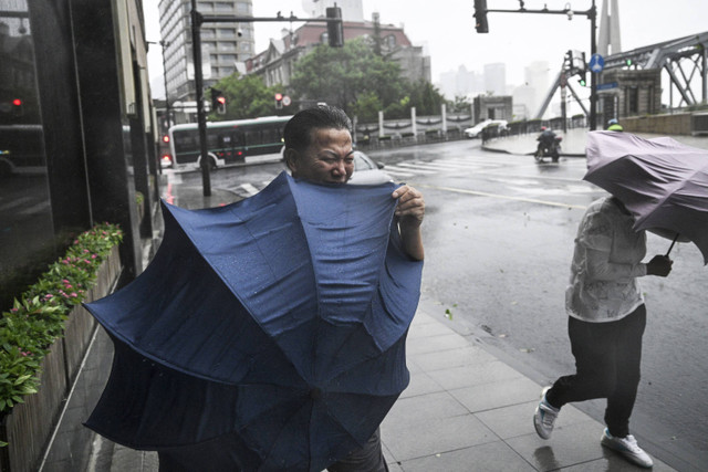 Para pejalan kaki berjuang dengan payung mereka di tengah angin kencang dan hujan akibat terjangan Topan Bebinca di Shanghai, Cina, Senin (16/9/2024). Foto: Hector Retamal/AFP