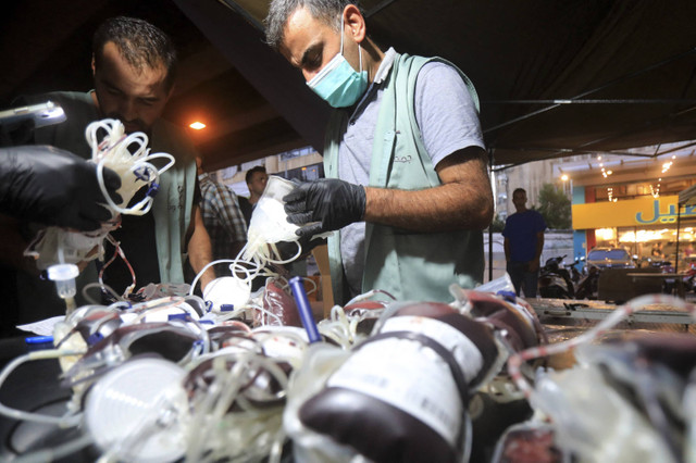 Petugas medis mengumpulkan donor darah di bawah tenda di pinggiran selatan Beirut, Lebanon ketika pager yang mereka gunakan untuk berkomunikasi meledak, Selasa (17/9/2024). Foto: MAHMOUD AL-ZAYYAT/AFP