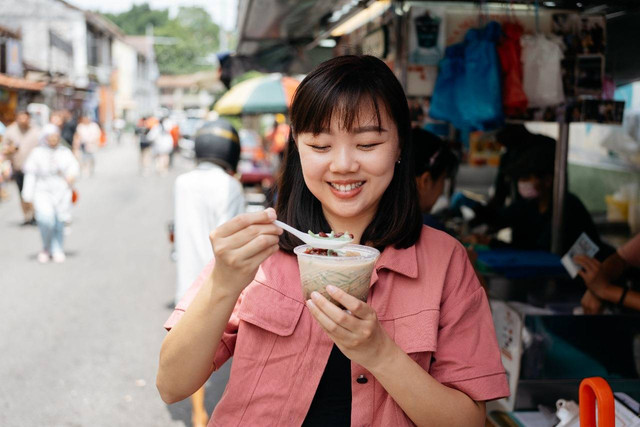 illustrasi turis mencicipi es cendol (Sumber : https://www.istockphoto.com/en/photo/asian-female-tourist-eating-shaved-ice-dessert-cendol-gm2151133788-572257981)