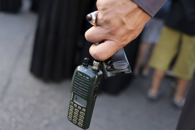 Seorang pria memegang perangkat walkie-talkie setelah ia melepas baterainya saat pemakaman korban yang tewas saat ratusan perangkat pager meledak di seluruh Lebanon di pinggiran selatan Beirut, Rabu (18/9/2024). Foto: Anwar Amro/AFP