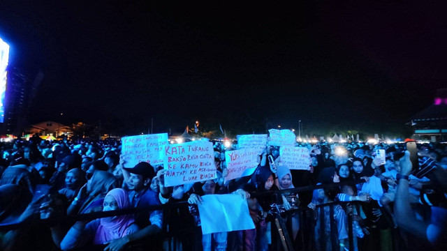 Emak-emak saat memperlihatkan poster di lokasi konser.