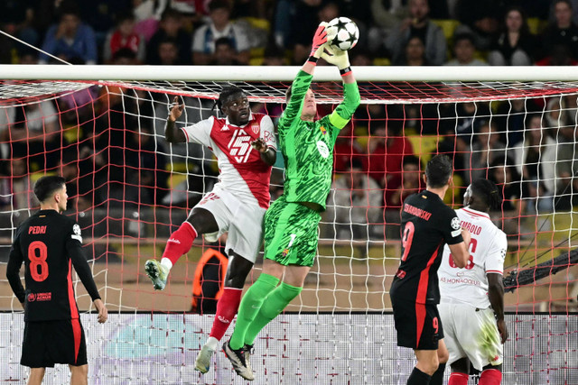 Penjaga Gawang Barcelona Marc-Andre Ter Stegen menangkap bola diudara saat berduel dengan pemain AS Monaco dalam pertandingan perdana Liga Champions di Stadion the Louis II, Monako, Kamis (19/9/2024). Foto: Miguel Medina/AFP