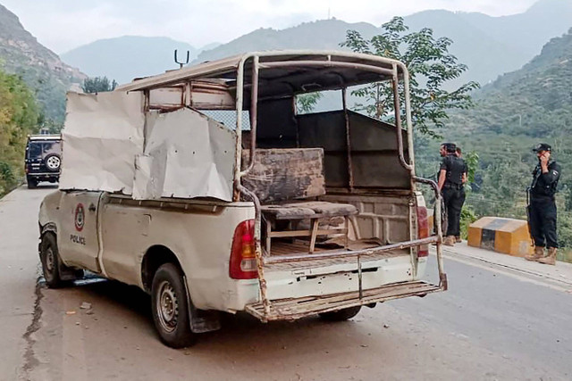 Petugas keamanan berdiri di dekat kendaraan polisi yang rusak di lokasi ledakan bom, di Malam Jabba di distrik Swat, provinsi Khyber Pakhtunkhwa, Pakistan, Minggu (22/9/2024). Foto: Mehboob UL HAQ / AFP