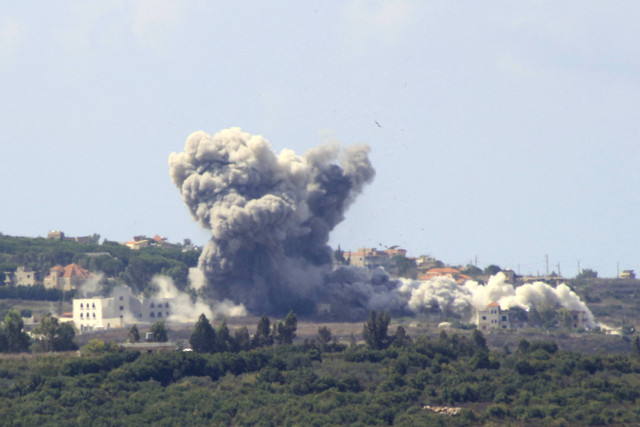 Asap mengepul dari lokasi serangan udara Israel di desa Tayr Harfa, Lebanon, dekat perbatasan Lebanon-Israel, Senin (23/9/2024). Foto: KAWNAT HAJU/AFP