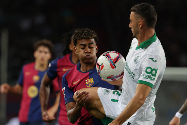 Pemain Barcelona Lamine Yamal berebut bola dengan pemain Getafe Juan Iglesias pada pekan ketujuh Liga Spanyol di Estadio Olimpic Lluis Companys, Barcelona, Rabu (25/9/2024). Foto: LLUIS GENE/AFP