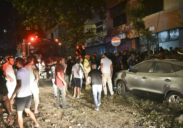 Orang-orang berkumpul di luar gedung apartemen yang terkena serangan udara Israel di distrik Cola, Beirut, Minggu (30/9/2024). Foto: FADEL ITANI/AFP