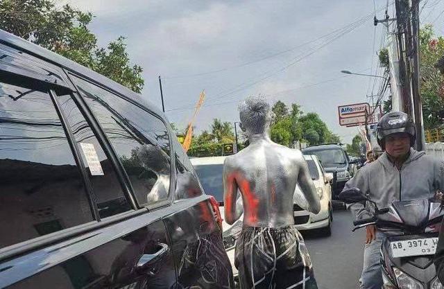 Seorang manusia silver yang tengah melakukan aksinya di tengah keramaian kendaraan yang melintas. Foto: Twitter/@GabrielCor53922